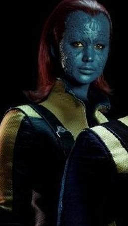 A torso shot of Jennifer Lawrence done up as Mystique: bright red hair, blue textured skin, yellow eyes. She is wearing a yellow and black jacket.